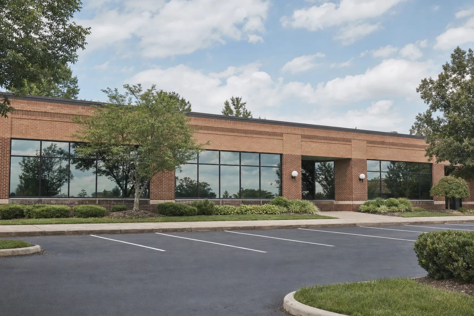 A low brick office building with filmed glass and a parking lot