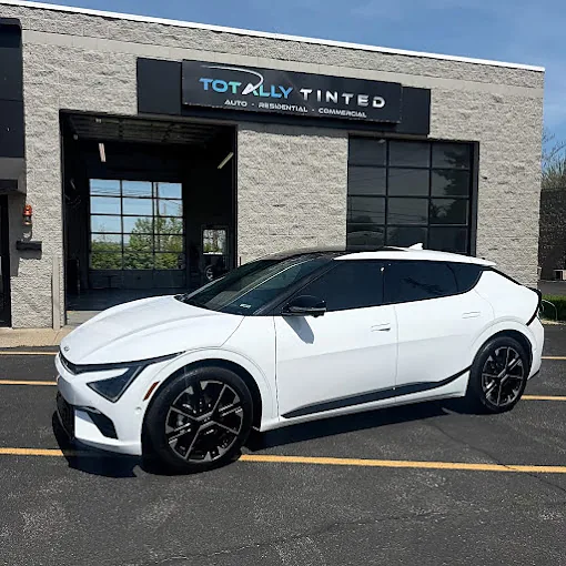 A white Kia EV6 with tinted windows outside the Totally Tinted shop