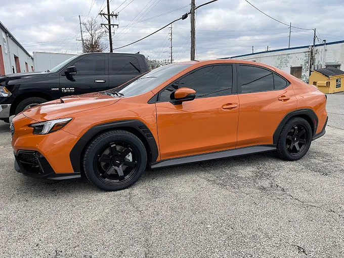 An orange Subaru WRX with tinted windows, a Totally Tinted job