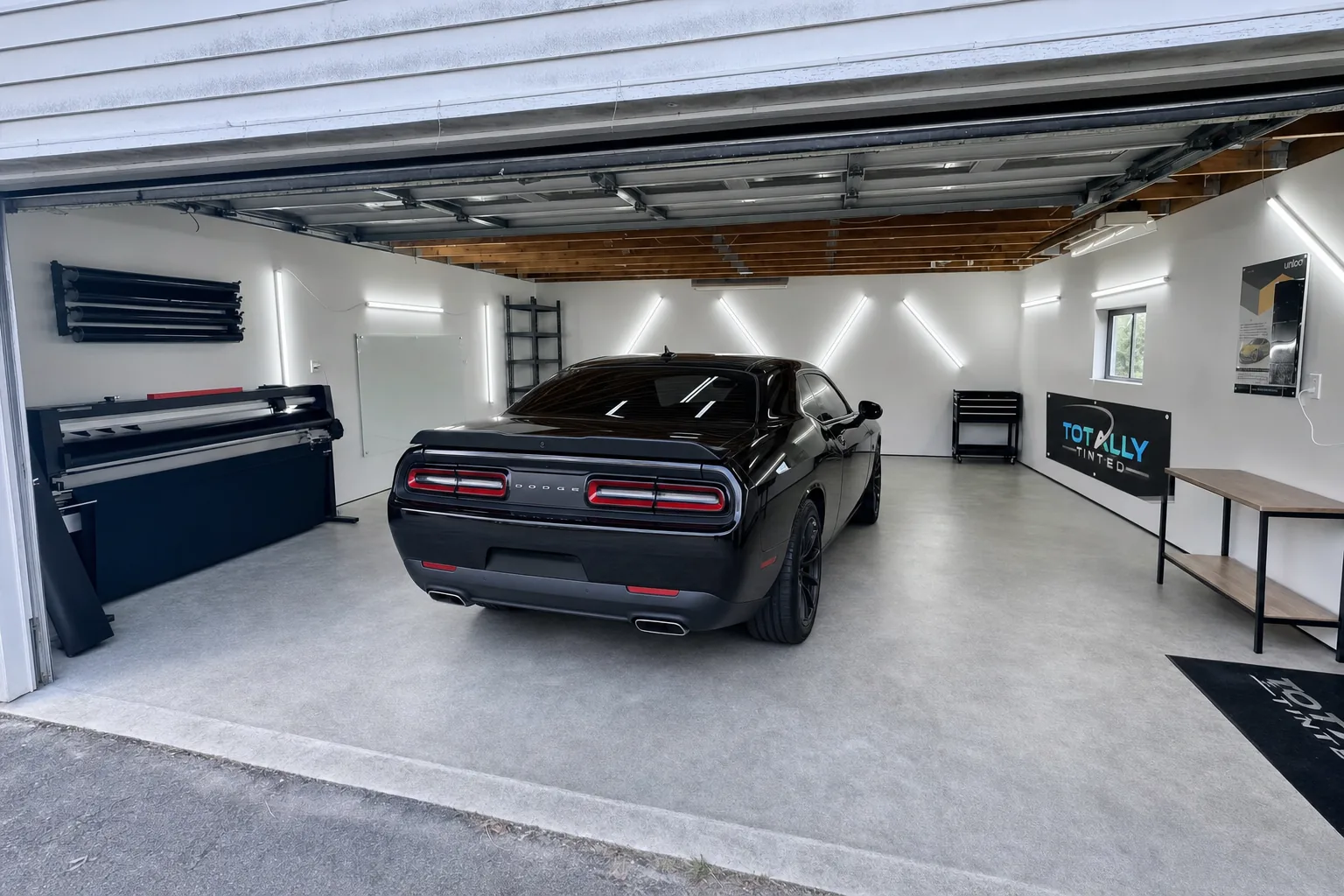 Gloss black Dodge Challenger with freshly tinted windows in the Totally Tinted garage studio