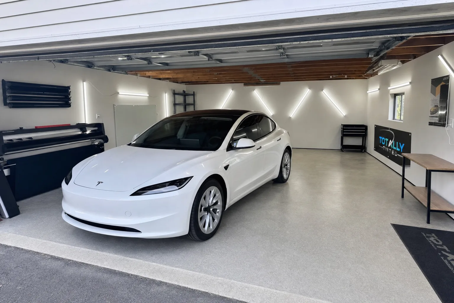 Pearl white Tesla Model 3 Highland with freshly tinted windows in the Totally Tinted garage studio