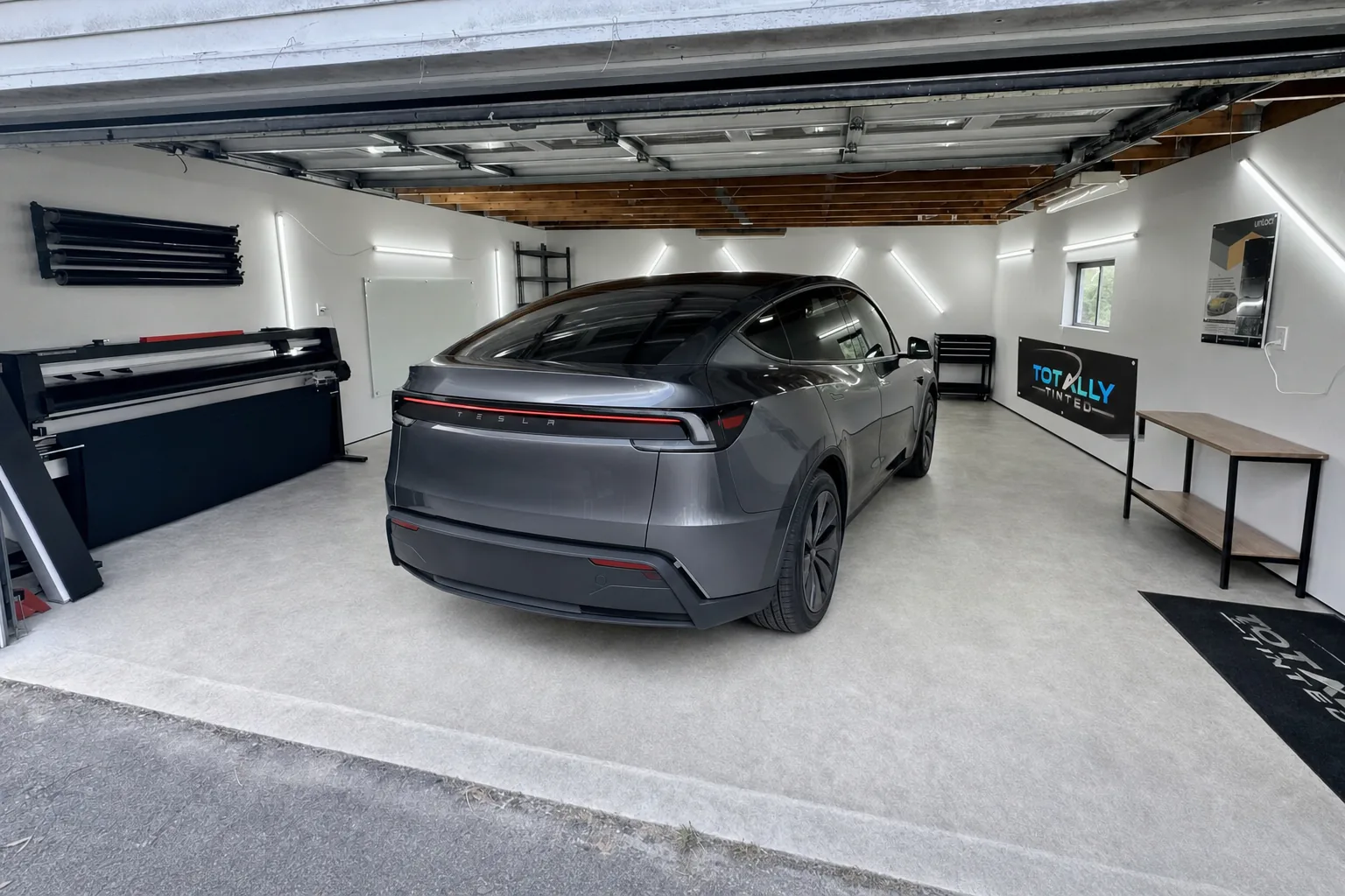 Graphite grey Tesla Model Y Juniper with freshly tinted windows in the Totally Tinted garage studio