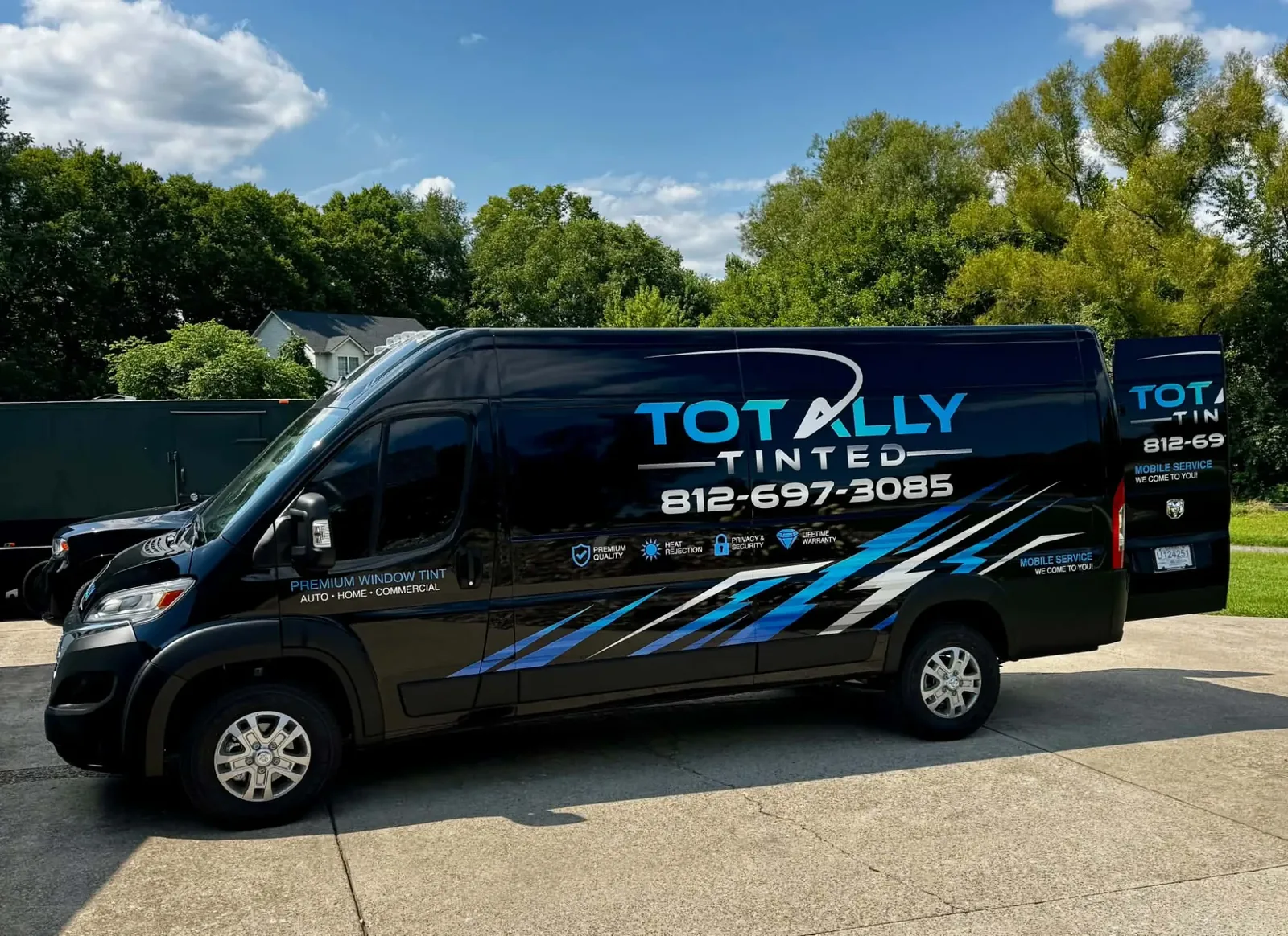 The Totally Tinted van parked on a driveway at a job, its back doors open