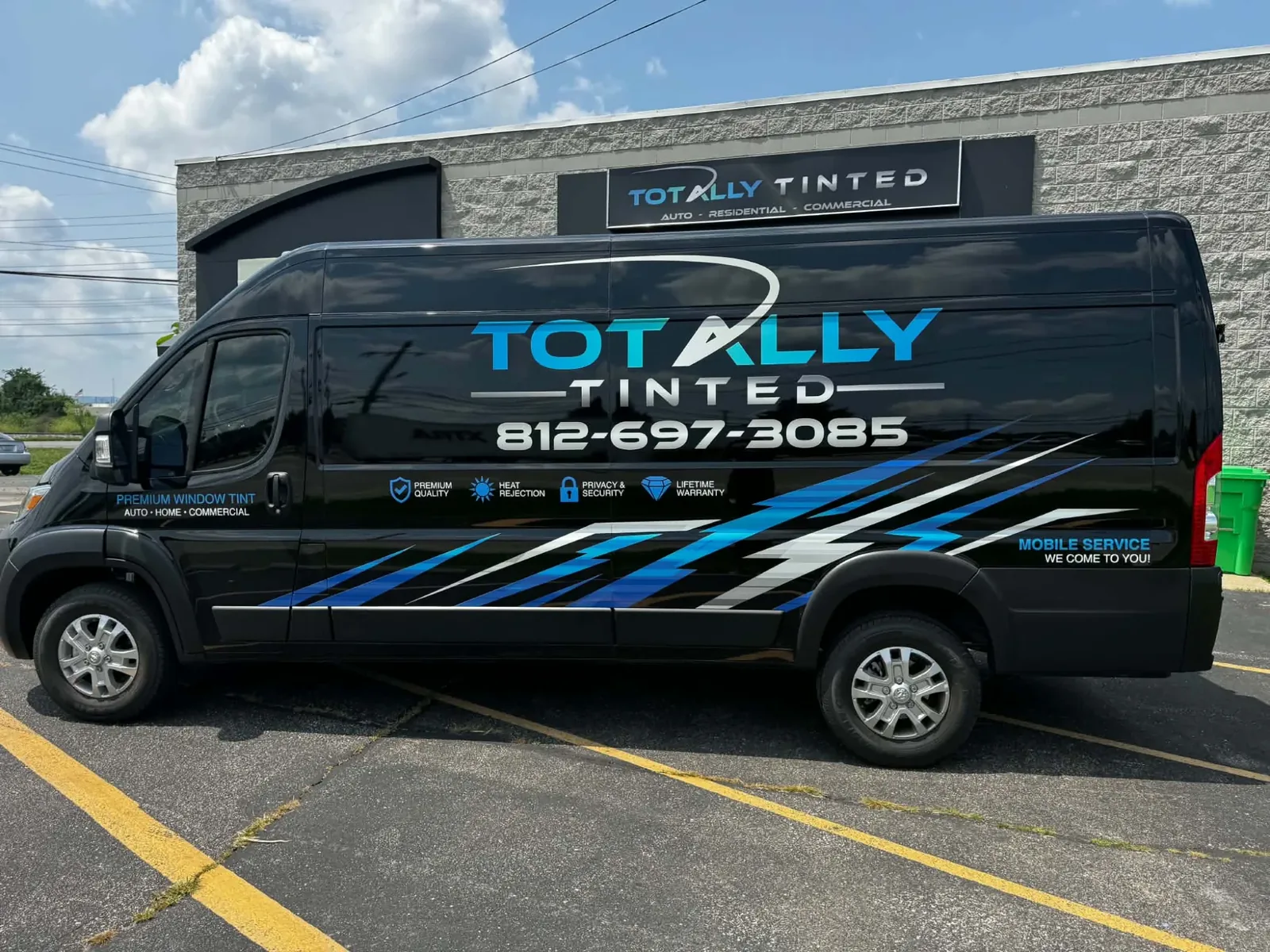 The Totally Tinted van parked outside their shop, its blue and silver livery and four emblems along the side